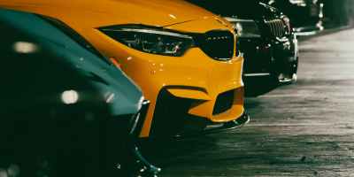 A close up shot of cars parked in a parking lot between white lines at night.
