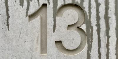 The number 13 etched into light gray wood with dark gray grains.