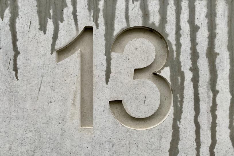 The number 13 etched into light gray wood with dark gray grains.