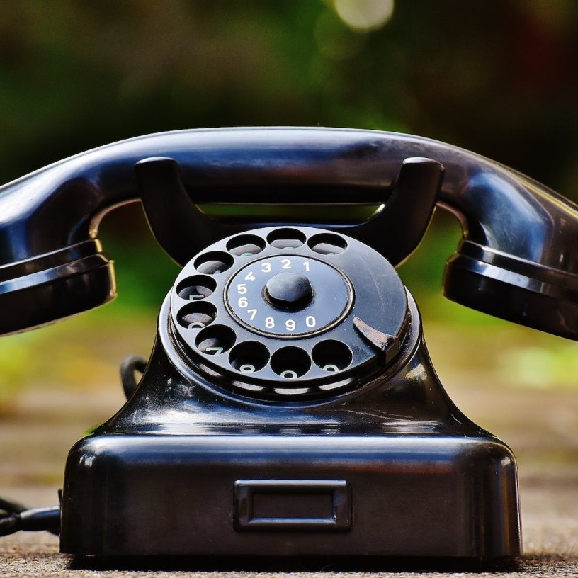 Close up photograph of an old-fashioned 1940's style black rotary dial telephone