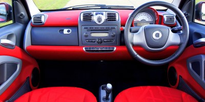 A British car with steering wheel on the right, red interior and the car radio in the middle.