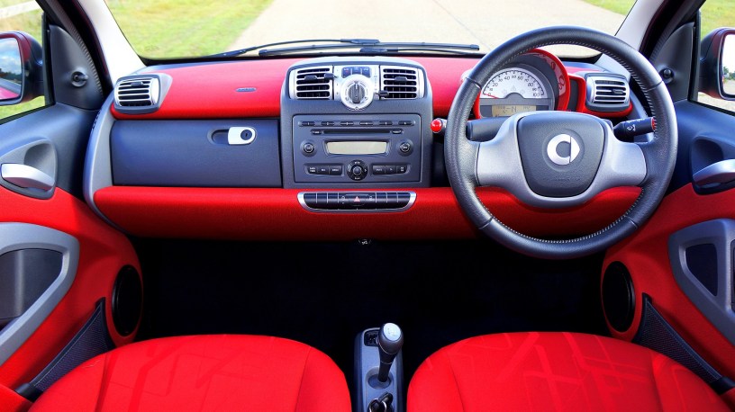 A British car with steering wheel on the right, red interior and the car radio in the middle.
