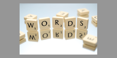 Scrabble tiles on a mirror with five tiles standing up: a W, an O, an R, a D and an S that spell out words.