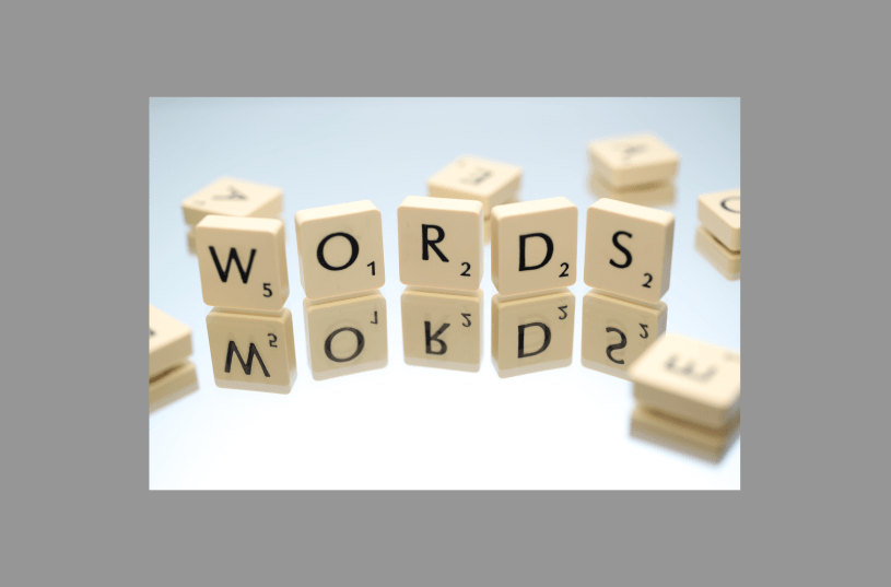 Scrabble tiles on a mirror with five tiles standing up: a W, an O, an R, a D and an S that spell out words.