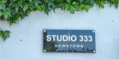 Green ivy covering above a white wall with a black sign that says Studio 333 Downtown