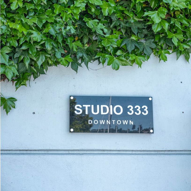 Green ivy covering above a white wall with a black sign that says Studio 333 Downtown