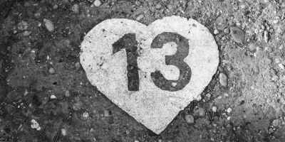 On gray rocky ground is a solid white heart with a number 13 cutout.