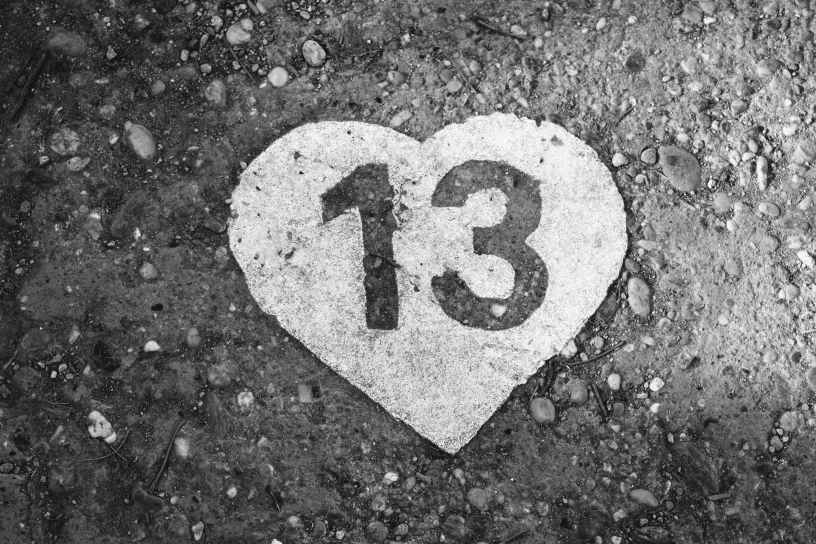 On gray rocky ground is a solid white heart with a number 13 cutout.