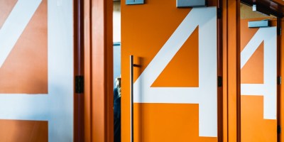 Three open, orange auditorium doors with the number four in white.
