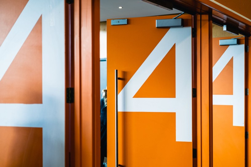 Three open, orange auditorium doors with the number four in white.