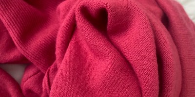 A fuchsia sweater in a clump with one fold forming a heart.
