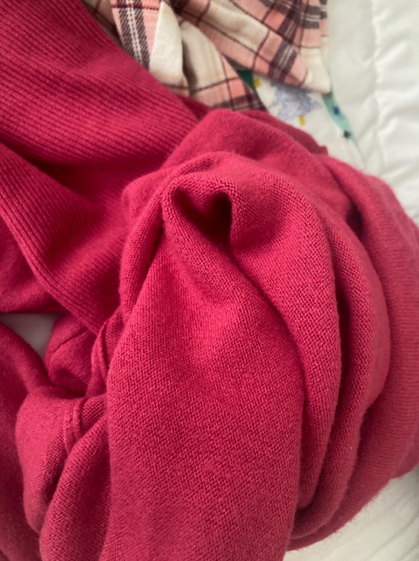 A fuchsia sweater in a clump with one fold forming a heart.