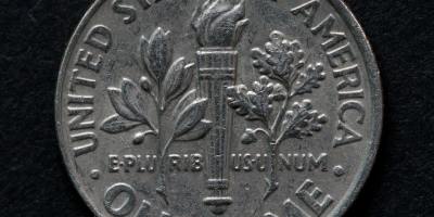 A silver dime on tails against a black background.