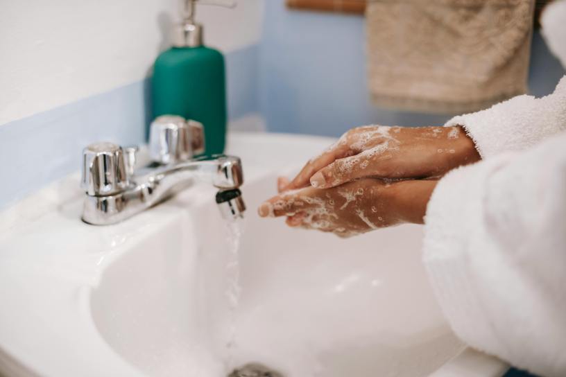 Two lathered hands being washed over a bathroom sink.