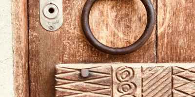 Decorated wooden panel and brass door knocker on an old door.