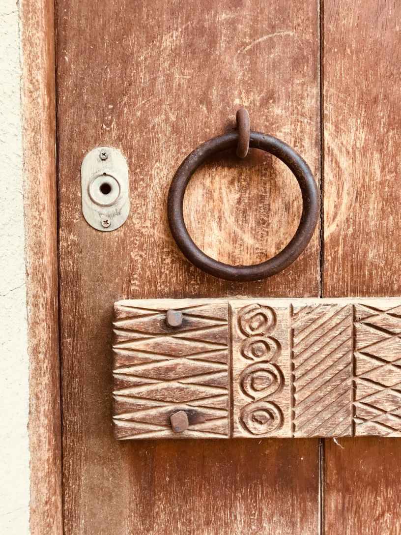 Decorated wooden panel and brass door knocker on an old door.